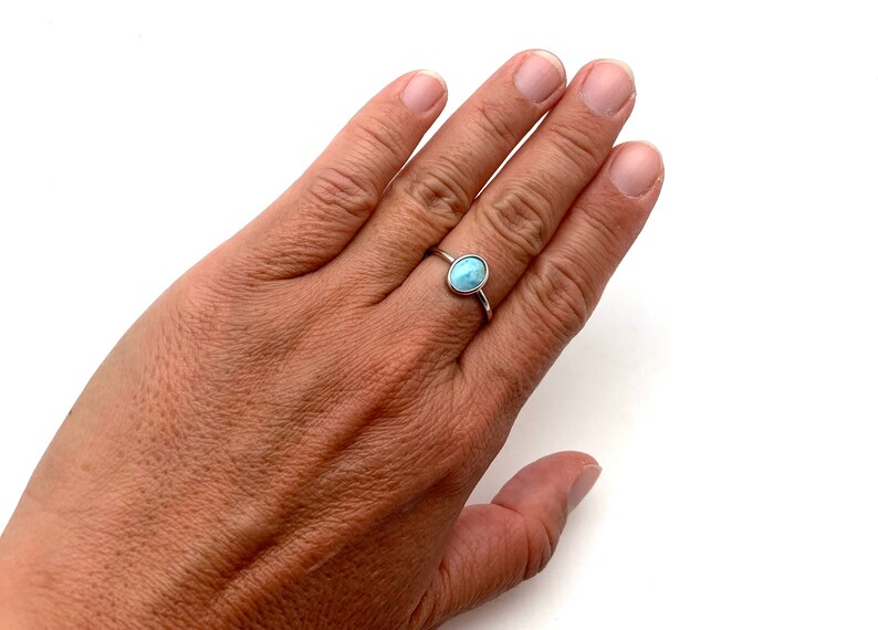 May include: A silver ring with a light blue oval gemstone.