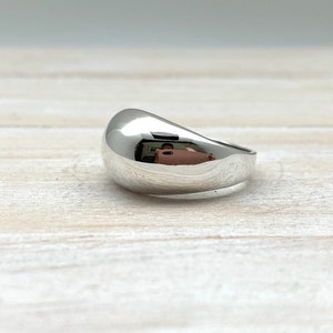 May include: A silver ring with a smooth, rounded, dome-shaped top.