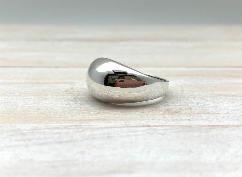 May include: A silver ring with a smooth, rounded, dome-shaped top.