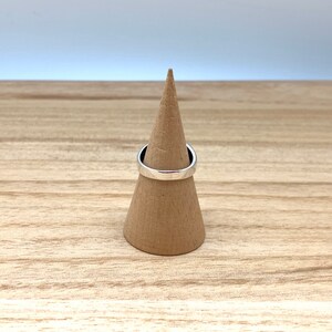 May include: A silver ring on a brown cone-shaped ring holder.