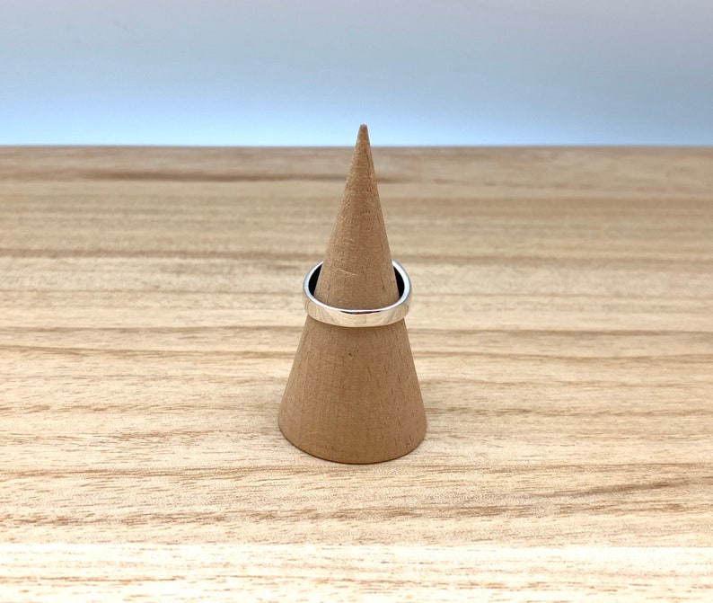 May include: A silver ring on a brown cone-shaped ring holder.