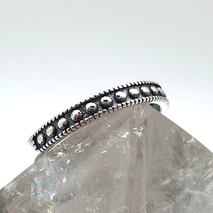 May include: A silver ring with a band of small, round beads.