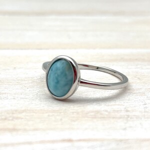 May include: A silver ring with a light blue oval-shaped gemstone.
