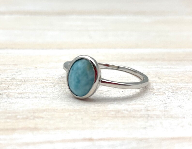 May include: A silver ring with a light blue oval-shaped gemstone.