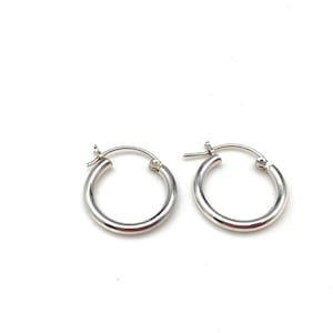 May include: A pair of silver hoop earrings. The earrings are simple and classic, with a smooth, polished finish.