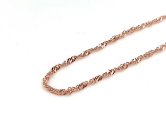 May include: A rose gold chain necklace with a delicate, twisted design.