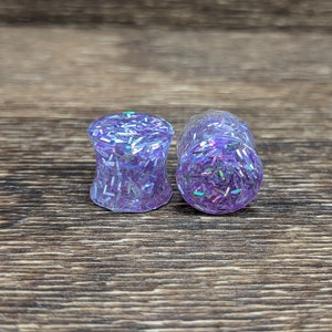May include: Pair of purple ear gauges with iridescent glitter embedded in the clear resin.