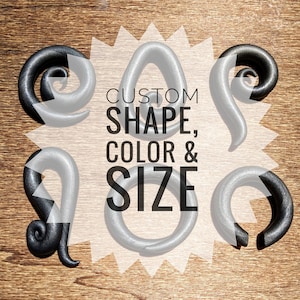 May include: Four different shapes of custom-made ear gauges in black and silver. The text "CUSTOM SHAPE, COLOR & SIZE" is displayed on a white background.