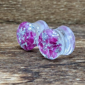May include: Pair of clear acrylic ear gauges with pink and silver glitter embedded inside.