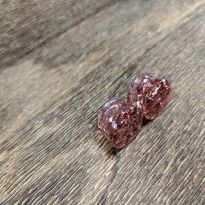 May include: Pair of pink and clear glitter ear gauges. The gauges are round and have a sparkly finish.