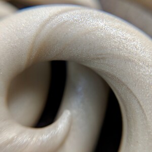 May include: Close-up of a white, textured, and slightly iridescent material that is twisted into a spiral shape.