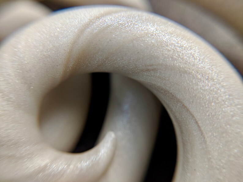May include: Close-up of a white, textured, and slightly iridescent material that is twisted into a spiral shape.