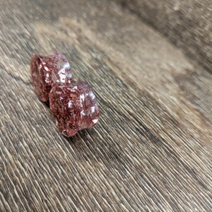 May include: Two clear resin ear gauges with a red and gold glitter embedded inside.