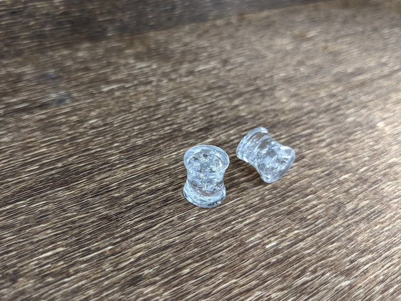 May include: Two clear glass ear gauges with a textured surface.