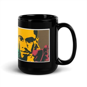 May include: Black ceramic mug with a striking graphic design. The image features a yellow and green face, and a figure in a red jacket. The mug has a large handle and a glossy finish, ideal for tea or coffee.