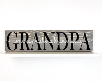 Peut inclure: Une pancarte en bois gris avec le mot "GRANDPA" en lettres noires. Les noms "Derrick", "Samantha", "Benjamin" et "Paige" sont écrits en cursive blanche avec des cœurs entre chaque nom.