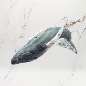 May include: A ceramic sculpture of a humpback whale, painted in shades of grey and white. The whale is depicted in mid-leap, with its mouth open and its flippers extended.