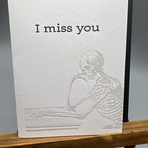 Tarjeta plegable con impresión tipográfica "Te extraño", en blanco por dentro