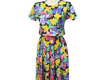 May include: A black dress with a floral print in shades of yellow, pink, purple, and green. The dress has short sleeves and a gathered skirt.