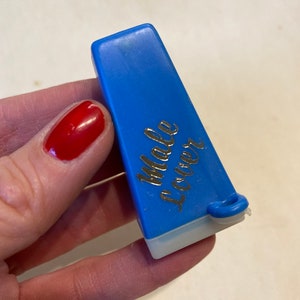 May include: A blue plastic sewing thread cutter with the words "Male Locker" printed on the side.