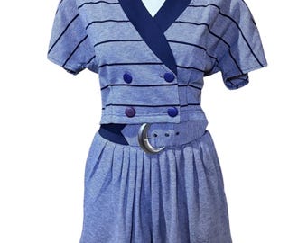 May include: A vintage blue and white striped two-piece outfit. The top has a V-neck, short sleeves, and decorative buttons. The shorts are pleated and belted with a silver-tone buckle. The outfit is displayed on a mannequin.