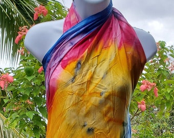 May include: A colorful tie-dye sarong with shades of blue, yellow, pink, and red. The sarong is draped over a mannequin and is made of a soft, flowing fabric.