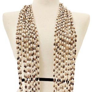 May include: A multi-strand necklace composed of numerous small, natural seashells. The shells are primarily white and brown, strung together to create a cascading effect. The necklace is displayed on a mannequin.