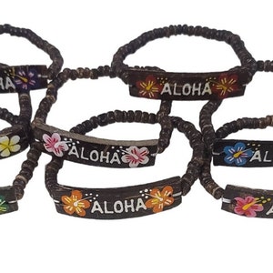 May include: Six brown coconut shell bracelets with the word "ALOHA" painted in white and decorated with colorful flowers.