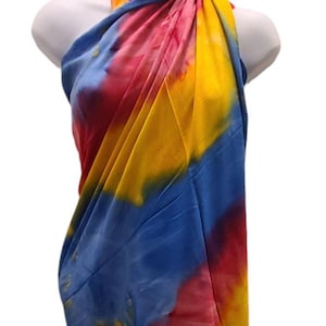 May include: A colorful tie-dye sarong in shades of blue, yellow, and red. The sarong is draped around a mannequin, showing how it can be worn as a beach cover-up.
