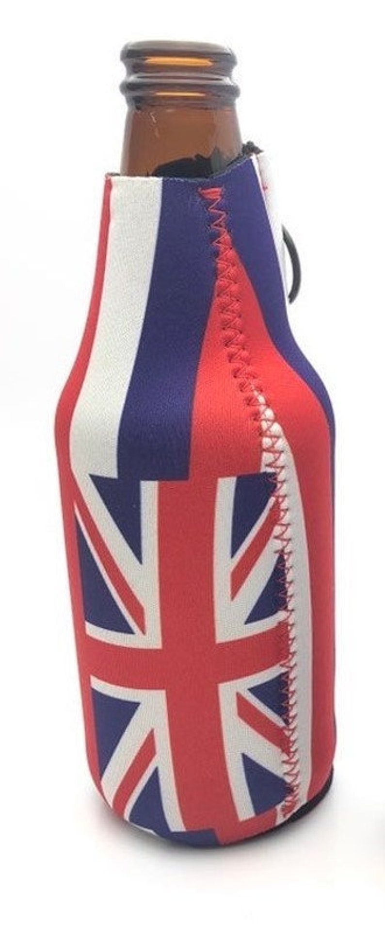 May include: A brown glass bottle inside a red, white, and blue Union Jack-themed beer can cooler. The cooler has a black loop and a red stitched seam. The design features the British flag.