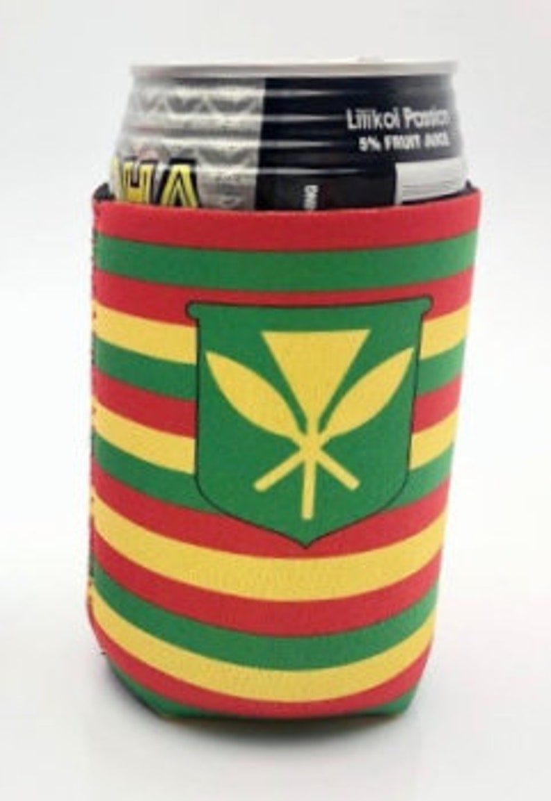May include: A colorful beverage can koozie with a Hawaiian design. The koozie features horizontal stripes in red, yellow, and green, with a green shield emblem containing a yellow symbol. The can inside is partially visible, showing a black and silver top.