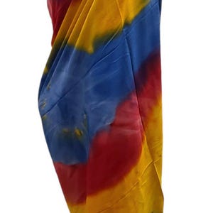 May include: A colorful tie-dye sarong with shades of blue, yellow, and red. The sarong is draped over a mannequin and is ready to be worn.