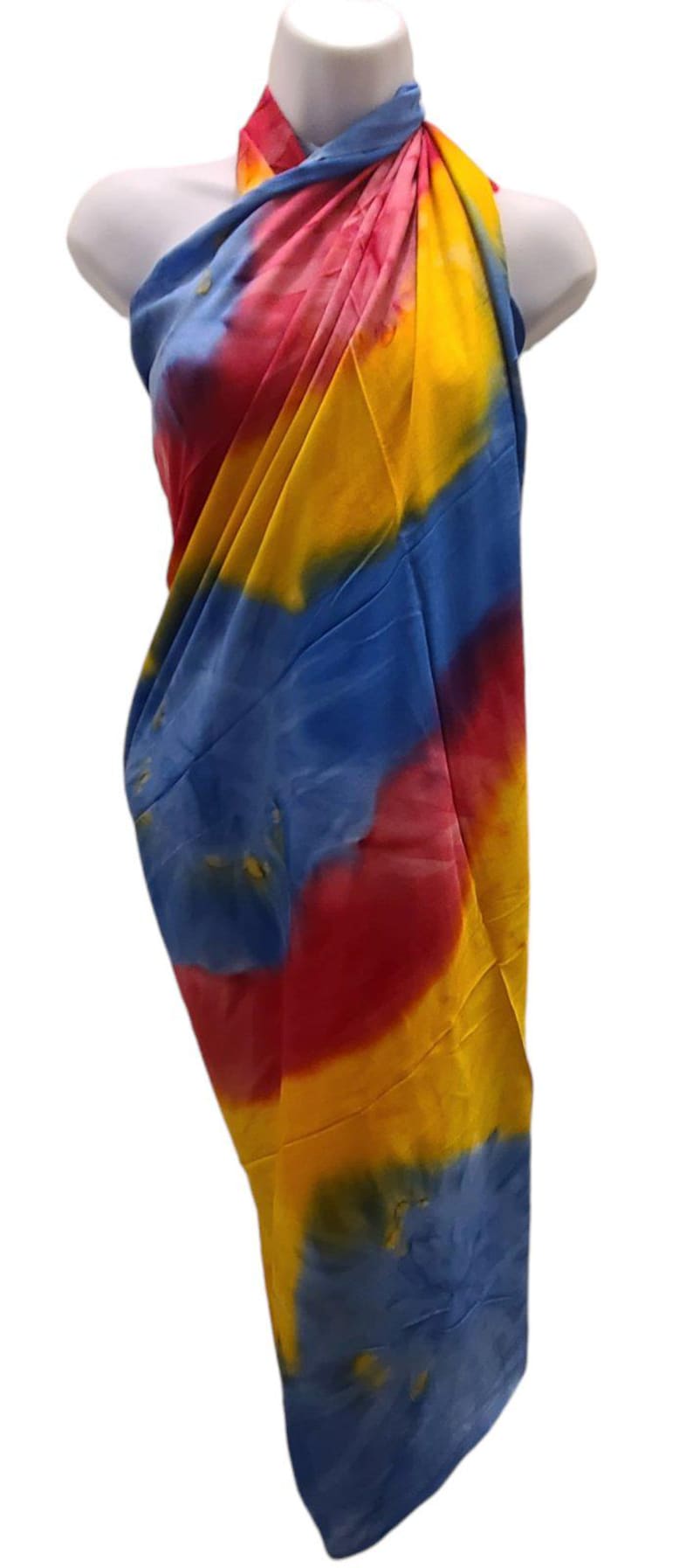 May include: A colorful tie-dye sarong with shades of blue, yellow, and red. The sarong is draped over a mannequin and is ready to be worn.