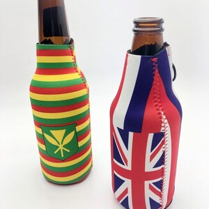 May include: Two brown glass bottles with colorful insulated sleeves. One sleeve features horizontal stripes of red, yellow, and green with a green emblem. The other sleeve displays the Union Jack flag and red, white, and blue stripes.