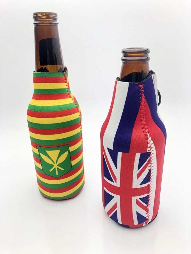 May include: Two brown glass bottles with colorful insulated sleeves. One sleeve features horizontal stripes of red, yellow, and green with a green emblem. The other sleeve displays the Union Jack flag and red, white, and blue stripes.