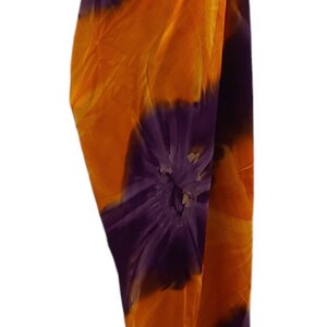 May include: A purple and orange tie-dye sarong with a floral pattern. The sarong is draped over a mannequin.