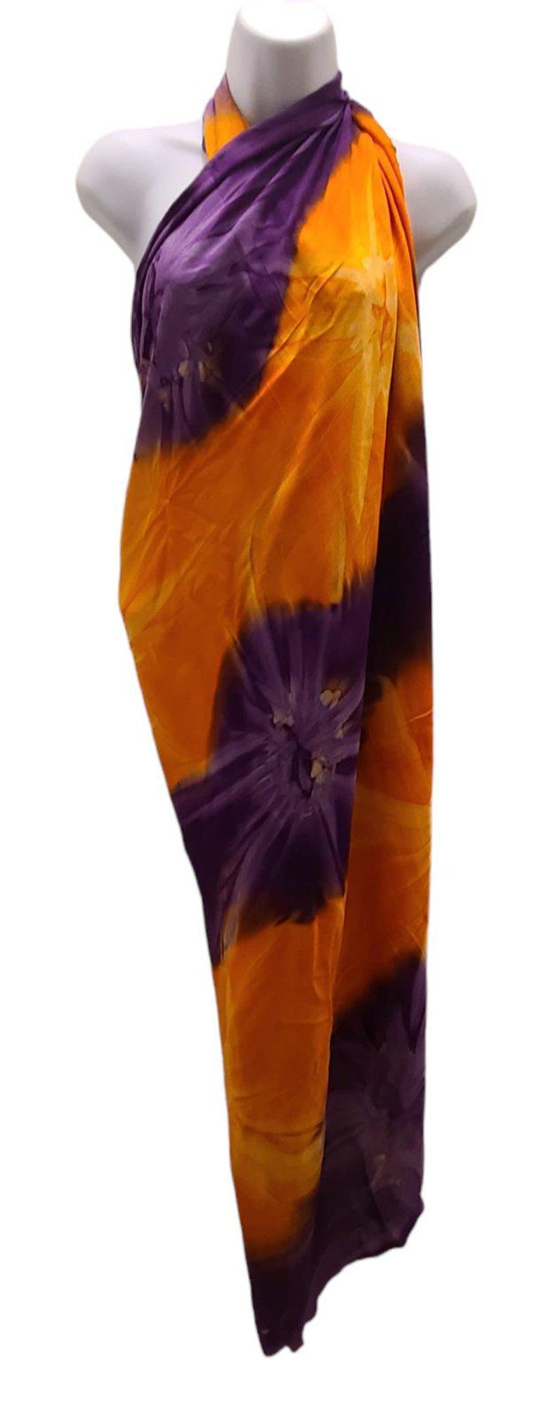 May include: A purple and orange tie-dye sarong with a floral pattern. The sarong is draped over a mannequin.