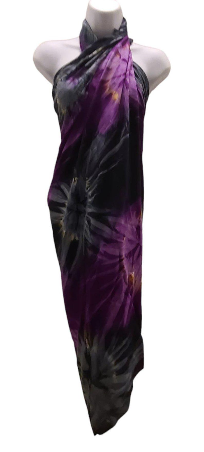 May include: A purple and gray tie-dye sarong with a floral pattern. The sarong is draped over a mannequin.
