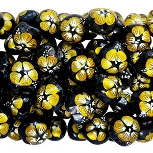 May include: A collection of black and gold beads with a floral design. The beads are round and have a glossy finish.