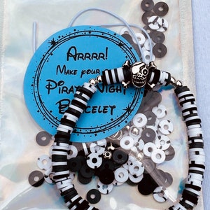 May include: A DIY pirate night bracelet kit with black and white striped beads, a skull charm, and black and white spacer beads. The kit comes in a clear plastic bag with a blue and white label that says "Arrrr! Make your Pirate Night Bracelet".