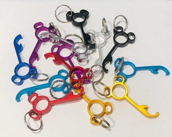 Könnte beinhalten: Eine Gruppe von bunten Schlüsselanhängern mit Flaschenöffner-Funktion. Jeder Schlüsselanhänger hat ein Mickey-Mouse-Kopf-Design in einer anderen Farbe. Die Schlüsselanhänger sind aus Metall und haben eine glänzende Oberfläche.