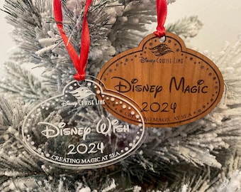 May include: Two Christmas ornaments, one clear acrylic and one wood, both shaped like name tags. The acrylic ornament says "Disney Wish 2024 Creating Magic at Sea" and the wood ornament says "Disney Cruise Line Disney Magic 2024 Creating Magic at Sea".