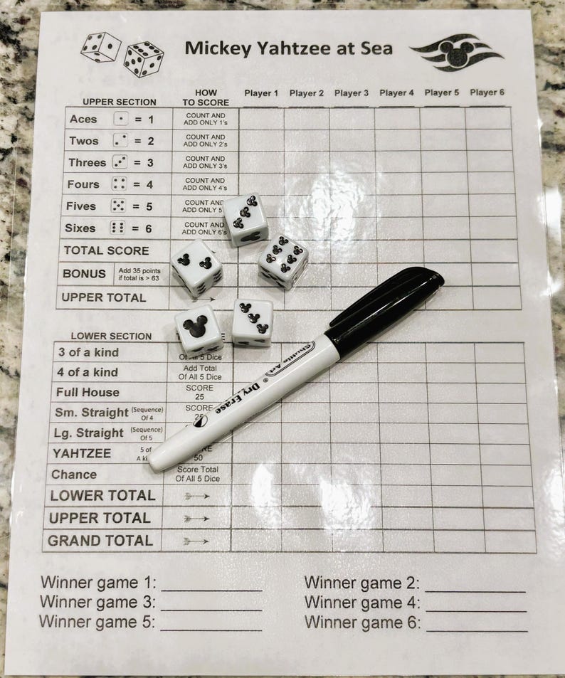 May include: A Mickey Yahtzee at Sea game set with a score sheet, dice, and a black marker. The dice are white with black pips and Mickey Mouse silhouettes. The score sheet has sections for scoring and player names.