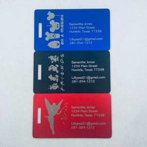 May include: Three luggage tags with different Disney character designs. The top tag is blue with Mickey Mouse and friends on a mission. The middle tag is black with Mickey Mouse and friends. The bottom tag is red with Tinkerbell. Each tag has the same contact information: Samantha Jones, 1234 Main Street, Humble, Texas 77338, Lillypad21@gmail.com, 281-354-1212.