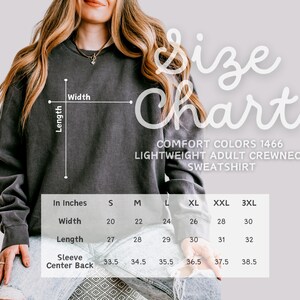May include: Dark gray Comfort Colors lightweight adult crewneck sweatshirt with a size chart. The chart shows measurements in inches for width, length, and sleeve center back for sizes S to 3XL.