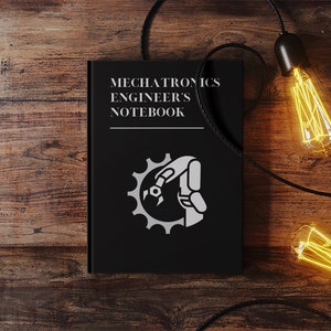 May include: A black notebook with the title "Mechatronics Engineer's Notebook" and a white icon of a robotic arm and gear on the cover. The notebook is on a wooden surface with two Edison bulb lights hanging from black cords.