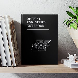 May include: A black notebook with the title "OPTICAL ENGINEER'S NOTEBOOK" in white text. A stylized eye with circuit board lines is featured on the cover.