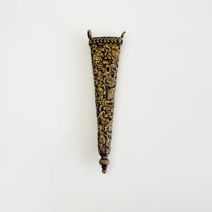 May include: A detailed, antique brass-colored vase with a flared, conical shape. The vase features intricate floral and foliate carvings across its surface, with small loop handles at the top and a rounded base. The overall design suggests a vintage or ornamental piece.