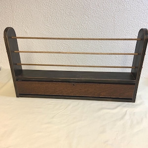 May include: A dark wood wall shelf with three horizontal shelves and a small drawer. The shelf has a rustic, vintage look.