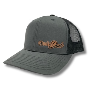 May include: A gray and black trucker hat with a brown leather patch that says "Only Dads" in a cursive font.